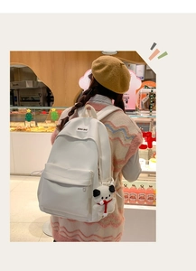 Close-up of minimalist white backpack featuring a zipper pocket and cute panda plush charm