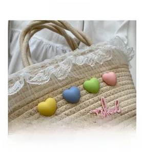 Detail shot of beige woven straw bag with white lace trim and macaron heart decorations