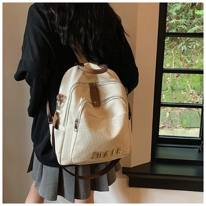 Détail d'un grand sac à dos beige avec motif matelassé et logo métallique chic