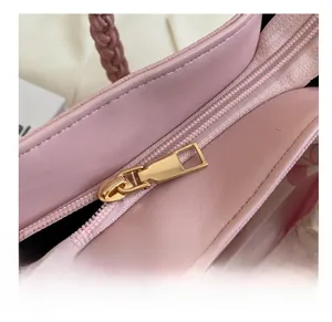 Detail of pink leather tote bag featuring a gold zipper and woven handle with silk scarf