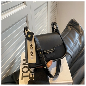 Detail of black leather crossbody bag with dual straps and metallic logo nameplate