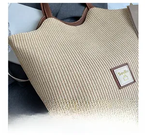 Vue macro de la texture en paille tressée et du logo en cuir marron sur le sac