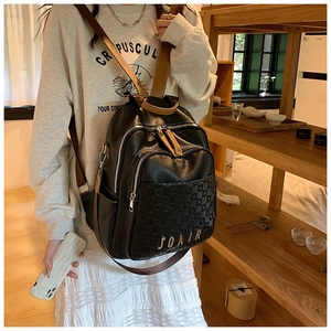 Détail d'un sac à dos en cuir noir avec logo JOAIR et motif en damier texturé