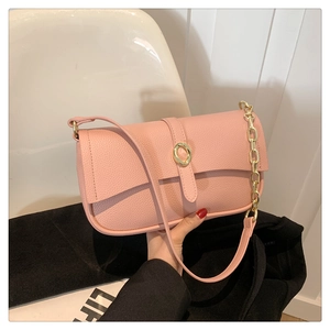 Dettaglio borsa rosa in pelle martellata con fibbia dorata e catena a maglie grandi