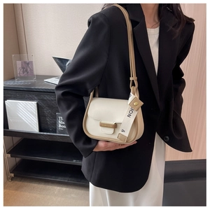 Detail of minimalist beige small square bag with brown trim and elegant ribbon accent
