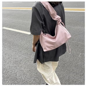 Outdoor shot of a pink crossbody bag featuring a unique knotted shoulder strap design