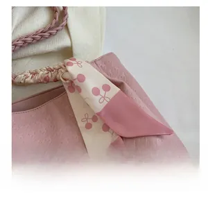Detail view of light pink tote bag featuring houndstooth texture and cherry print silk scarf