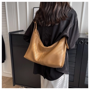 Detail of camel leather large capacity hobo bag on shoulder showing texture and slouchy fit