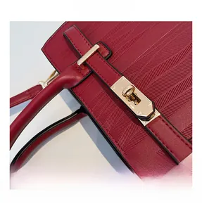 Macro shot of burgundy textured leather bag with luxury gold lock buckle detail
