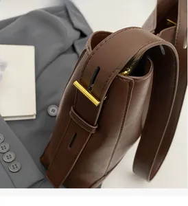 Dettaglio di una borsa a secchiello in pelle marrone con finitura lucida e dettagli dorati