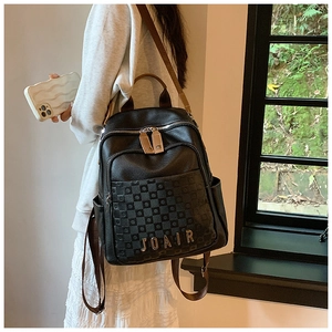 Détail d'un sac à dos noir en cuir grainé avec motif damier et logo JOAIR en métal doré