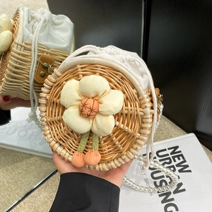 Handmade round straw crossbody bag with pearl strap and white floral charm detail