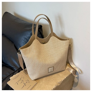 Détail du sac cabas en paille tressée avec logo en cuir et bords festonnés