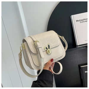Macro detail of the cream crossbody bag featuring rabbit embossing and golden metal lock