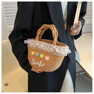 Detail of woven straw handbag featuring lace trim and colorful 3D heart embroidery