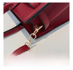 Detail of red leather bag showing golden metal hooks and fine textured stitching