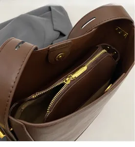 Dettaglio borsa a secchiello in pelle marrone con interno a doppio strato e zip oro