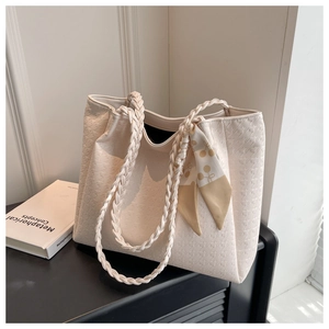 Detail of off-white tote bag with houndstooth texture, woven handle and silk scarf accessory