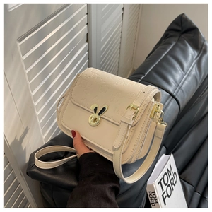 Close-up of beige crossbody bag with embossed bunny motifs and a cute metal rabbit clasp