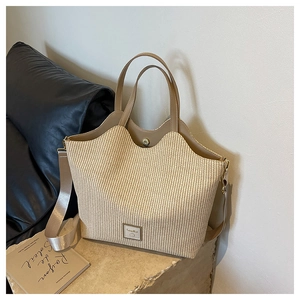 Détail d'un sac cabas en paille tissée avec bordure en cuir marron et sangle