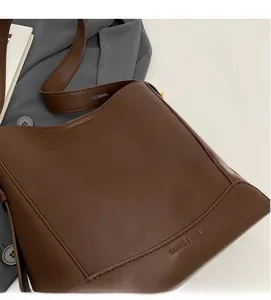 Dettaglio della borsa a secchiello in pelle marrone con logo impresso e tracolla regolabile