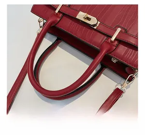 Detail showing red leather handbag with herringbone texture and gold metal turn-lock