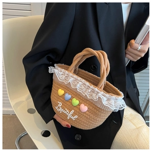 Detail of woven straw handbag featuring lace trim, colorful heart charms, and embroidery