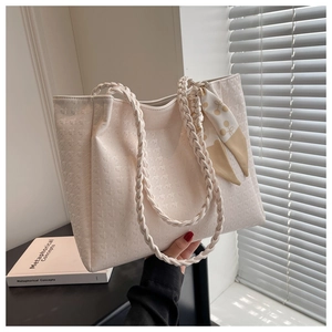 Detail of cream tote bag with star embossed texture and woven rope handle accents