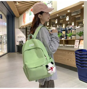 Close-up of light green nylon backpack with front pocket and cute dog plush pendant