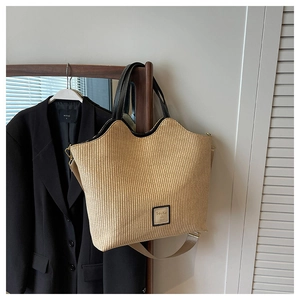 Détail du sac cabas en paille tressée avec bordure en cuir noir et large bandoulière