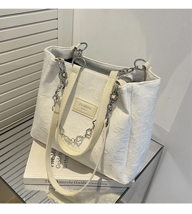 Détail du sac fourre-tout à fleurs gaufrées avec chaîne argentée et étiquette mode