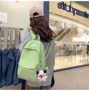 Detailed back view of mint green water-resistant backpack with a cute dog keychain