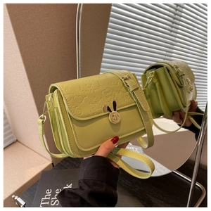 Detail of avocado green crossbody bag with rabbit ear lock and embossed patterns