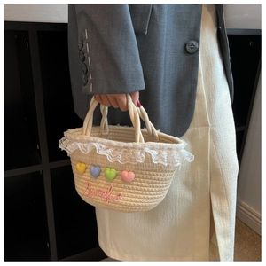 Detail of hand-woven straw bag featuring colorful hearts and lace trim in a lifestyle setting
