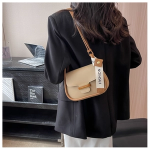 Detail of khaki crossbody bag with metal buckle and fashion ribbon on office background