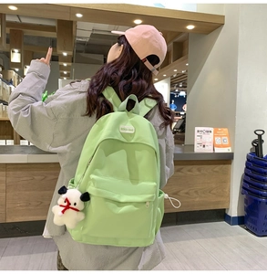 Light green nylon backpack featuring a front zipper pocket and cute white plush dog charm
