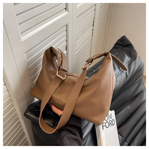 Close-up of brown lychee texture leather shoulder bag with golden metal adjustment buckle
