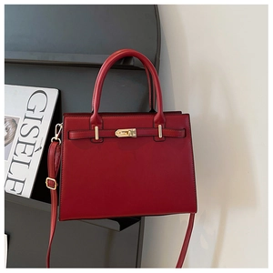 Detail of red leather handbag showing metal turn-lock closure and adjustable strap