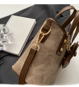 Close-up of brown textured leather bucket bag featuring gold hardware and heart charm