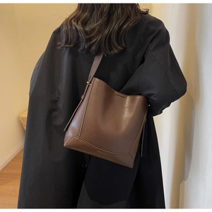 Dettaglio della base della borsa a secchiello con logo goffrato e finiture in metallo