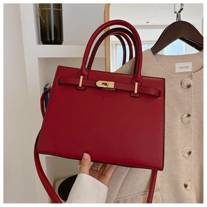 Close-up of deep red leather handbag with elegant gold twist lock and fine stitching