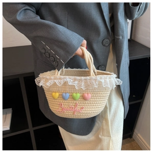 Detail of hand-woven straw handbag with lace trim and colorful 3D heart accents