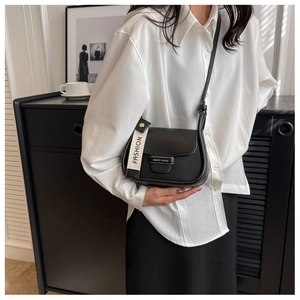 Detail of a chic black crossbody bag featuring a fashion letter strap and gold metal hardware