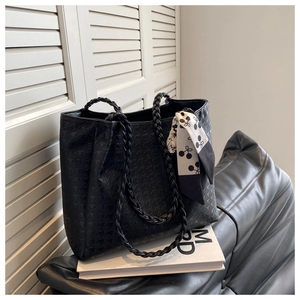 Detail of black tote bag featuring star embossed texture and decorative printed silk scarf