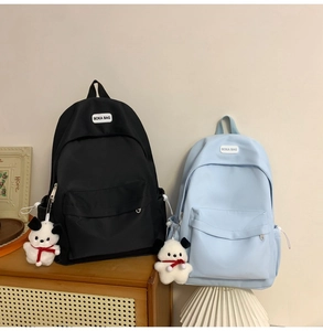 Detail of minimalist nylon backpacks in black and blue with a cute plush dog pendant