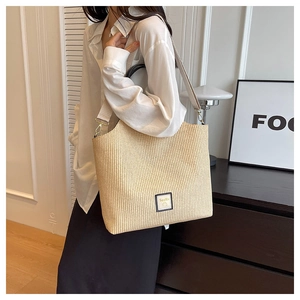 Détail d'un sac cabas tissé beige avec doubles poignées et bandoulière réglable