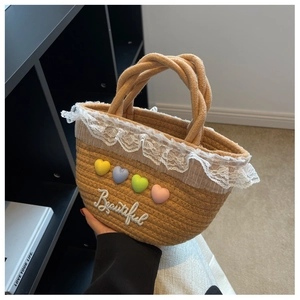 Detailed view of woven straw tote bag with lace trim and colorful heart charms