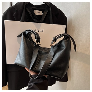 Detail view of black litchi pattern leather hobo bag with gold hardware and wide strap