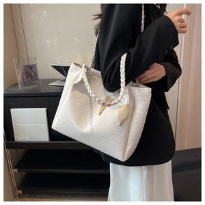 Detail of white quilted tote bag with woven handle and elegant silk scarf decoration