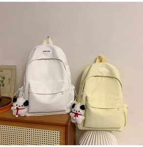 Detail view of minimalist white and yellow backpacks with cute plush dog charms